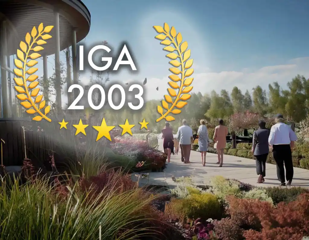 Auszeichnungs-Badge „IGA 2003“ über einem Foto von Besuchern auf einem Weg durch ein Beet mit Ziergräsern